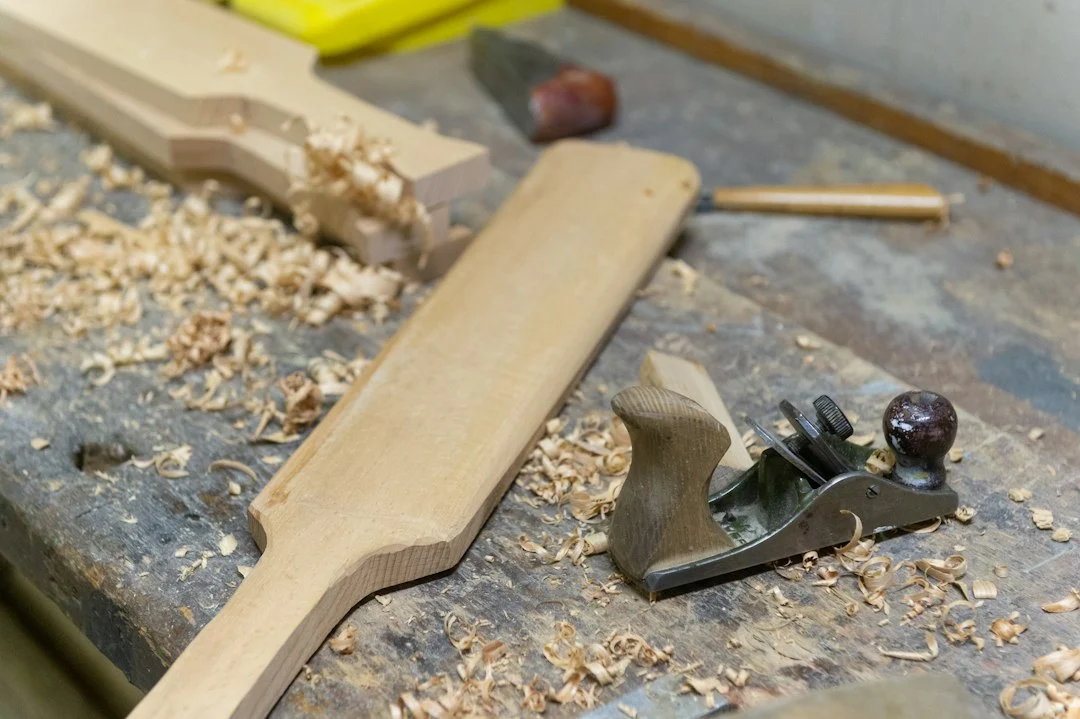 Hand plane and wood shavings on a workbench – preparing a glued laminated timber panel surface before gluing and finishing